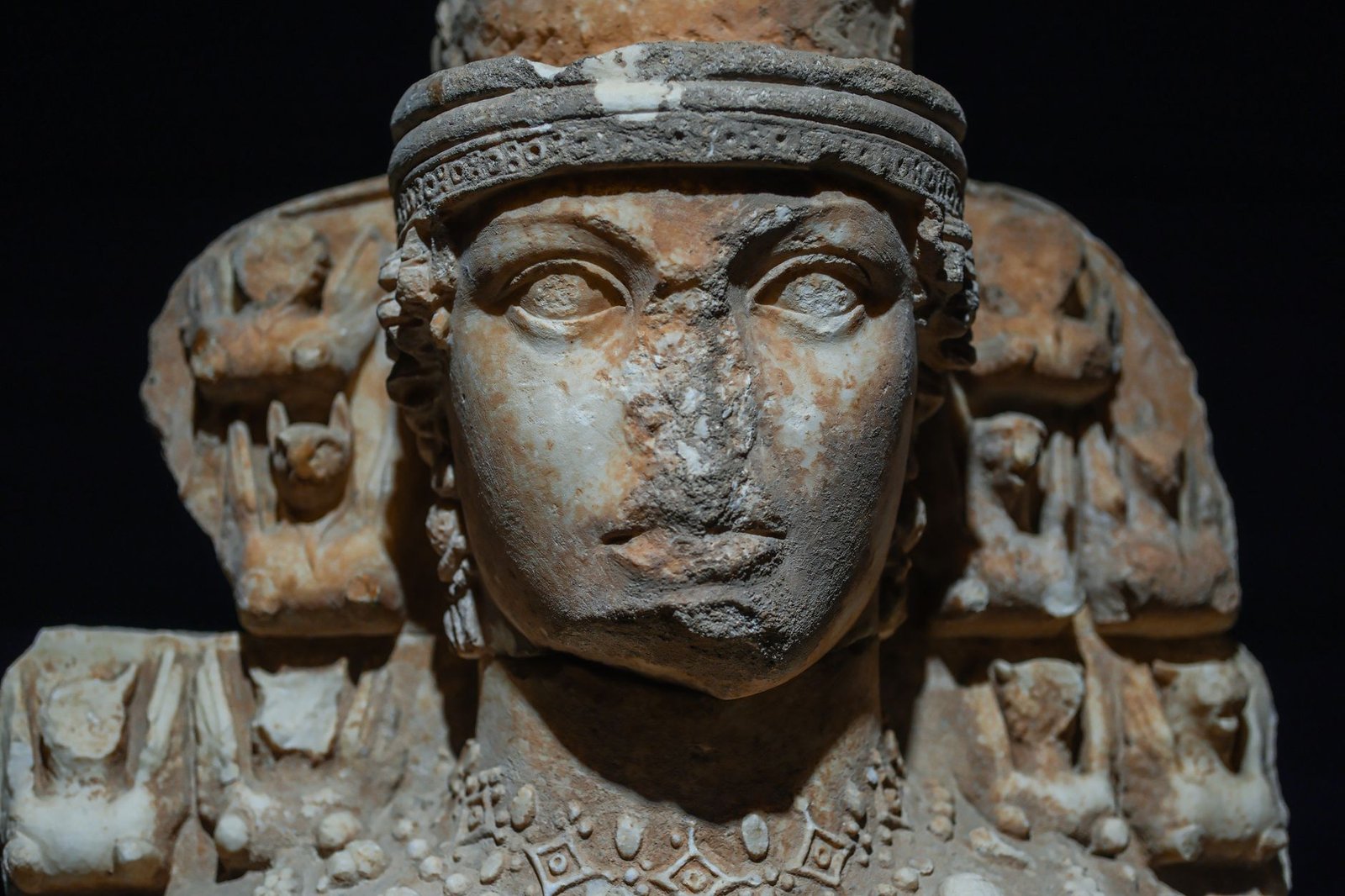 Ancient stone sculpture of a multi-faced deity with intricate carved details and weathered surface.