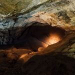 Naturally lit rocky cave interior with textured walls, evoking the Amaterasu cave myth
