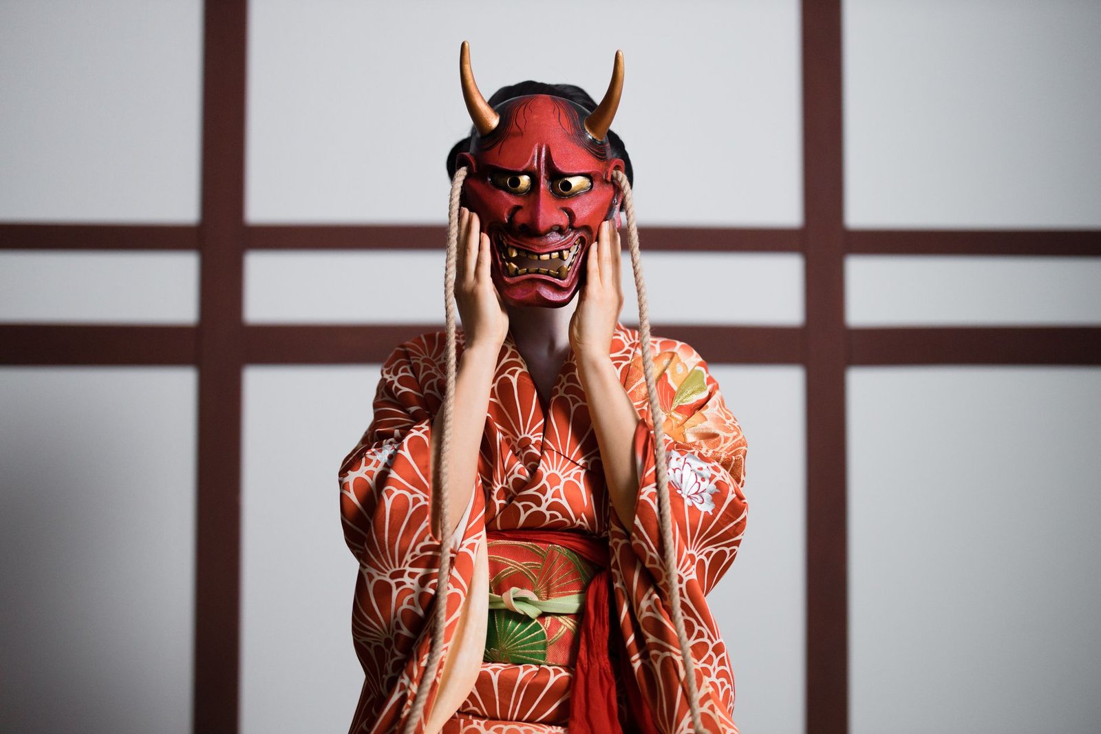 Person in a traditional Japanese kimono wearing a red oni demon mask, evoking Ame-no-Uzume myth through dance and dawn inspir