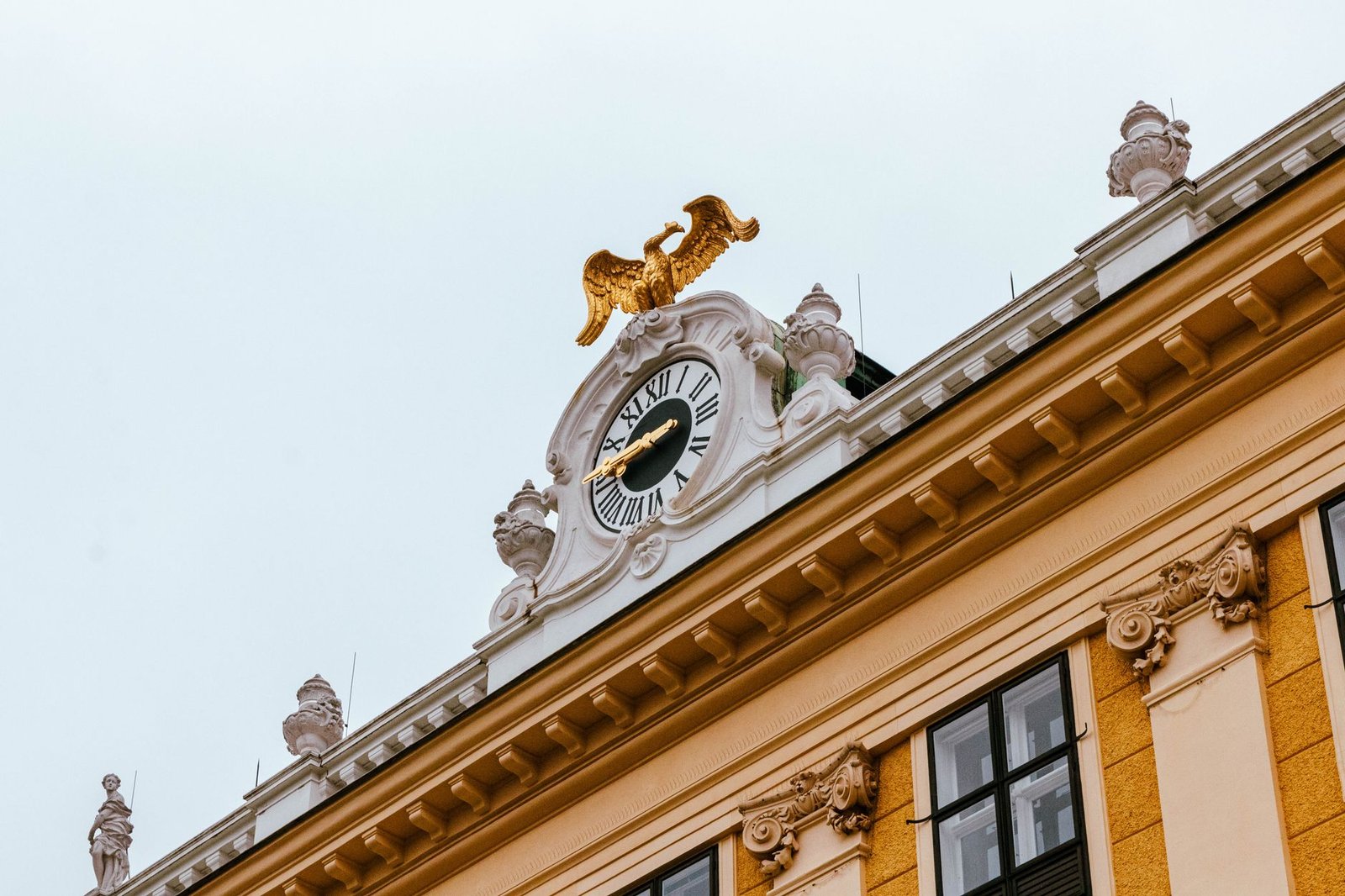 Ornate clock topped with a golden lion statue on a historic yellow building facade