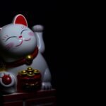 Maneki Neko cat figurine with gold coins on a black background