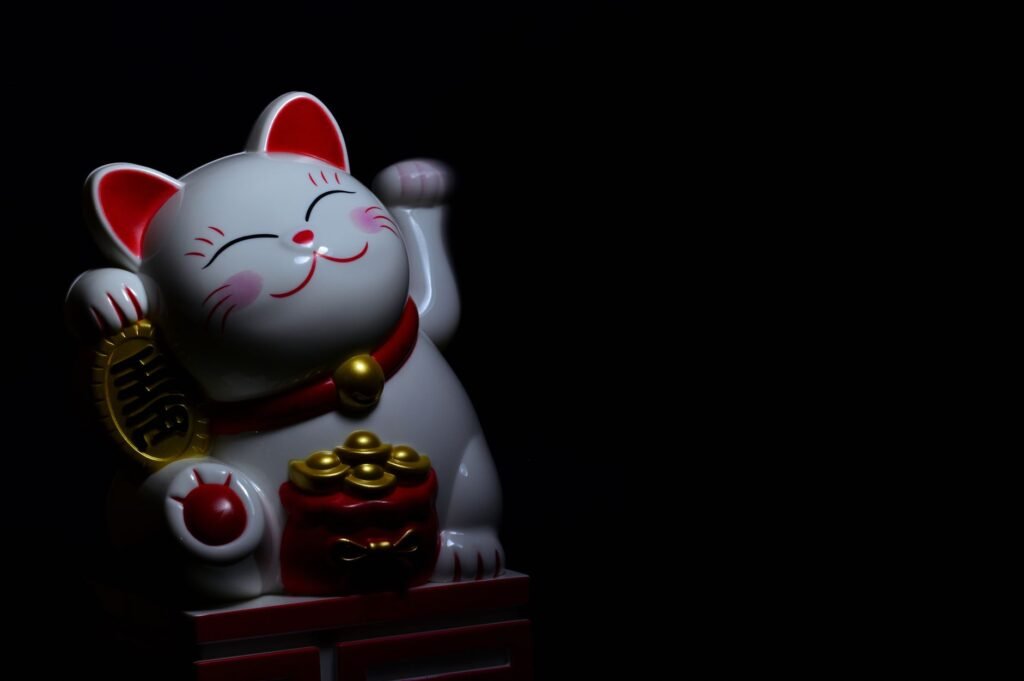 White Maneki-neko cat figurine with gold coins on a black background