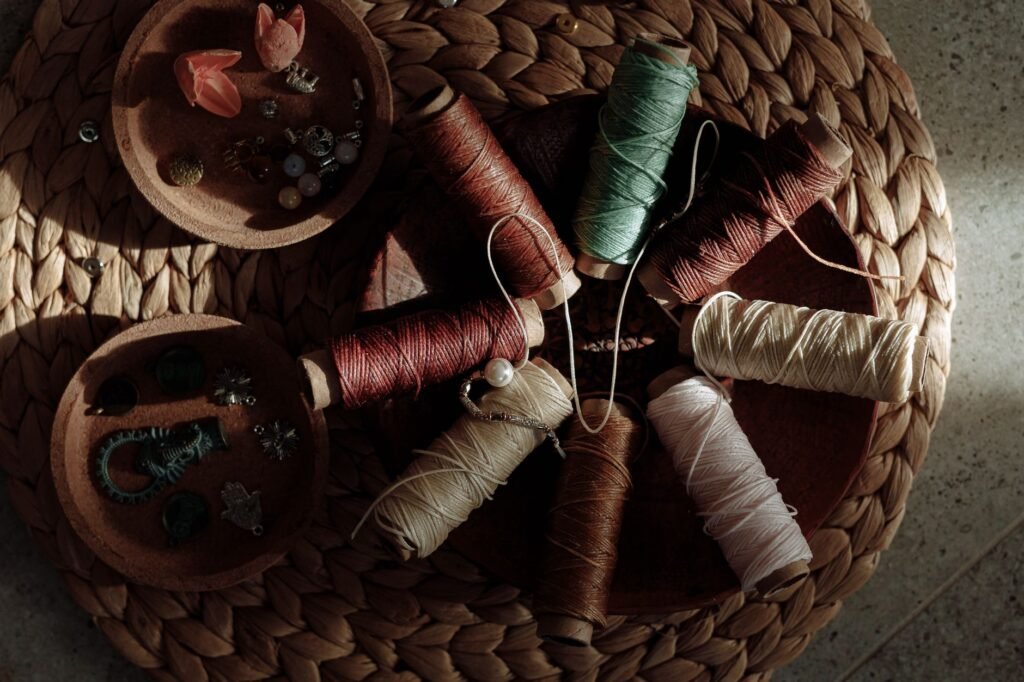 Colorful spools of thread and sewing accessories arranged on a woven mat, evoking Ariadne’s thread and the Minotaur myth