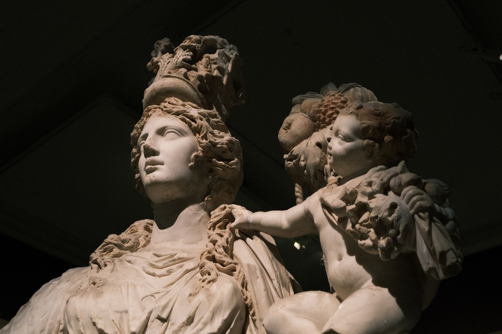 Close-up of an ancient marble statue of a woman with a headdress, flanked by cherubs, likely the Roman goddess Aurora