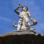 Statue of Balor, a muscular mythological figure holding a club against a blue sky