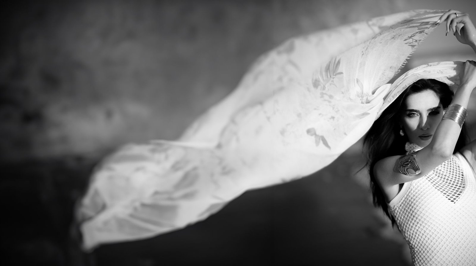 Black and white portrait of a woman with flowing fabric draped around her shoulders and arm