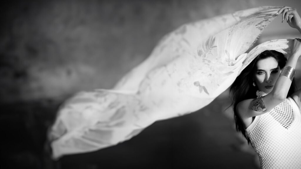 Black-and-white artistic photo of a woman with flowing fabric, evoking a mythic Bellerophon and the Chimera scene