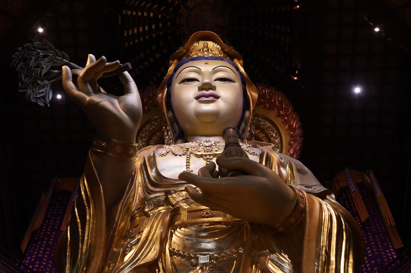 Golden Buddha statue holding a lotus flower inside a temple interior