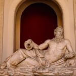 Ancient marble statue of a reclining bearded man with scroll, evoking the birth of Zeus in Cretan cave myth
