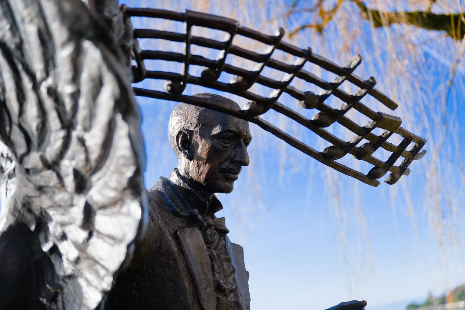 Metal sculpture of Mercury with a musical staff above his head, viewed in close-up.