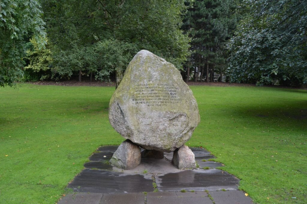 Memorial stone monument in a park with green grass and trees, commemorating Cú Chulainn