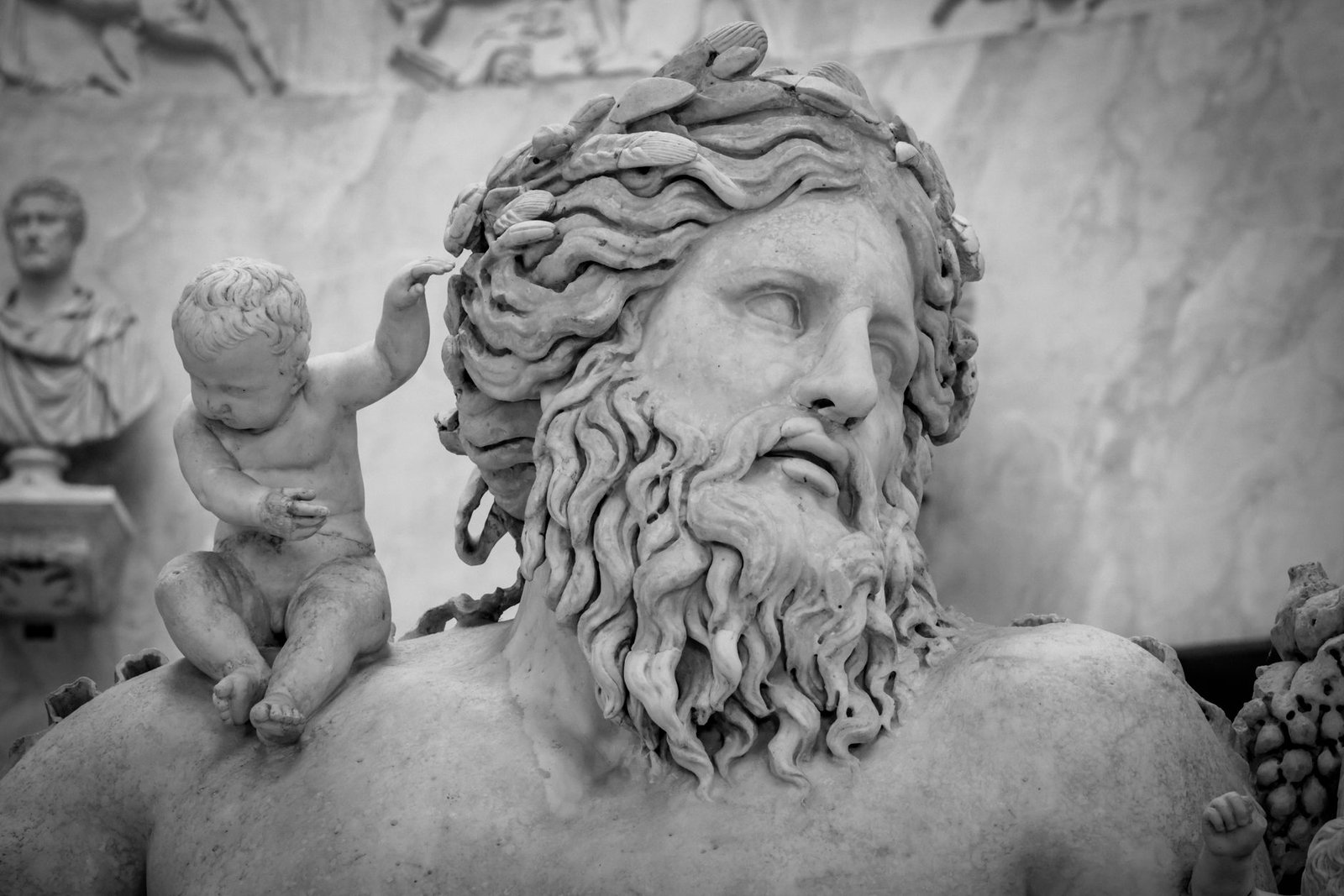 Ancient marble statue of a bearded man with a small cherub on his shoulder.