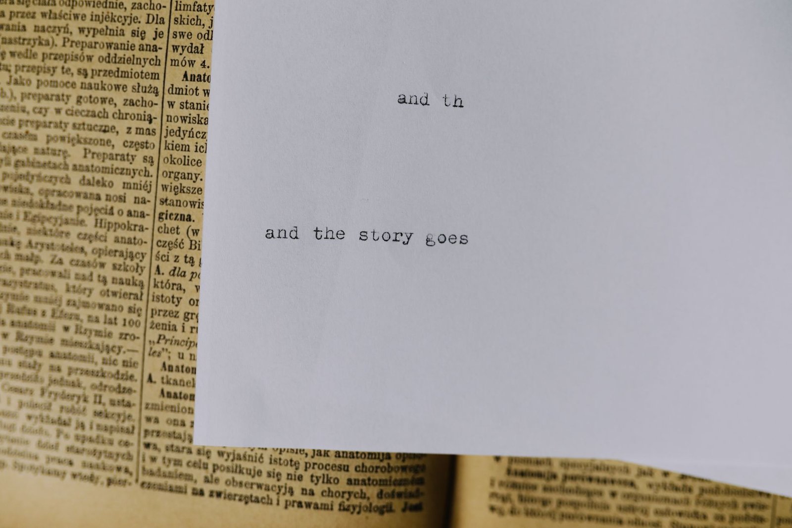 Close-up of typed phrase and the story goes on white paper resting over an open book
