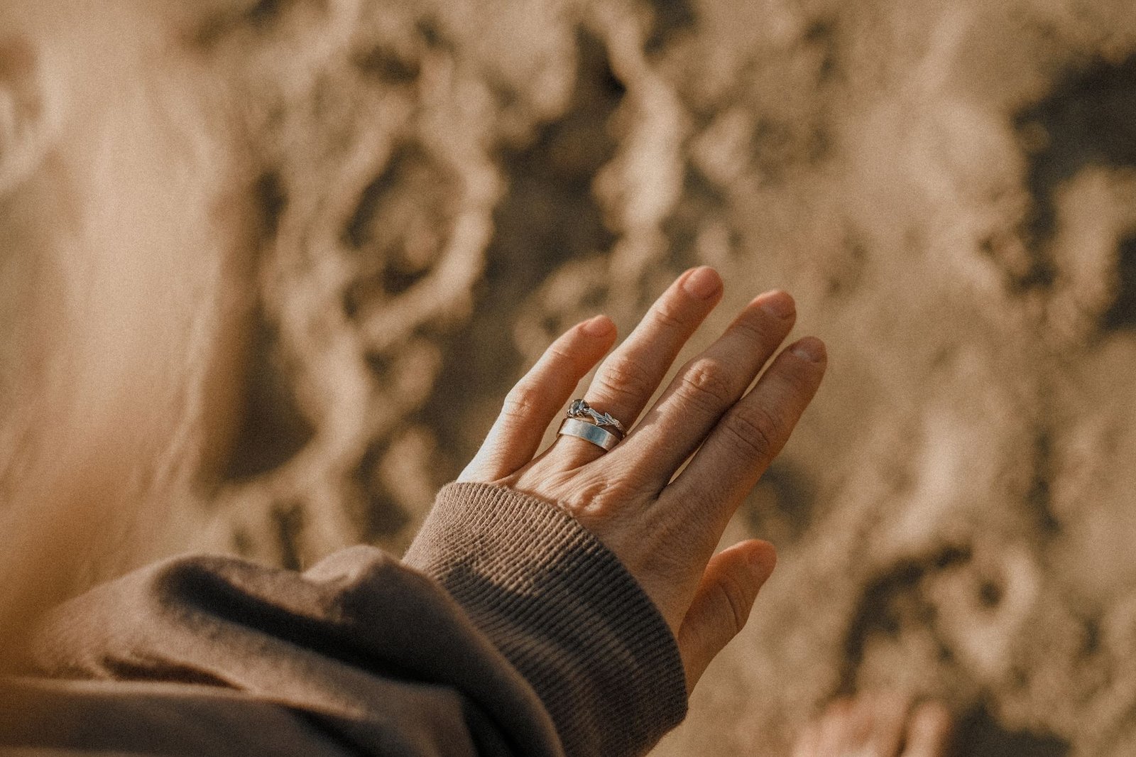 Close-up of a hand wearing a Claddagh ring against a blurred natural background
