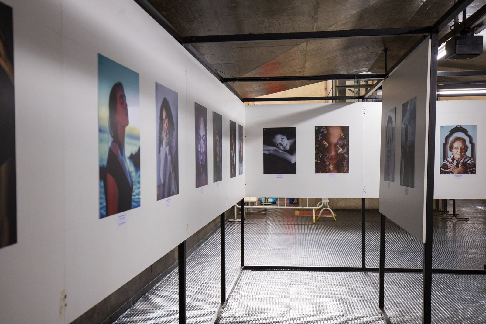 Portrait photography displayed in a modern industrial art gallery with white walls, track lighting, and framed images