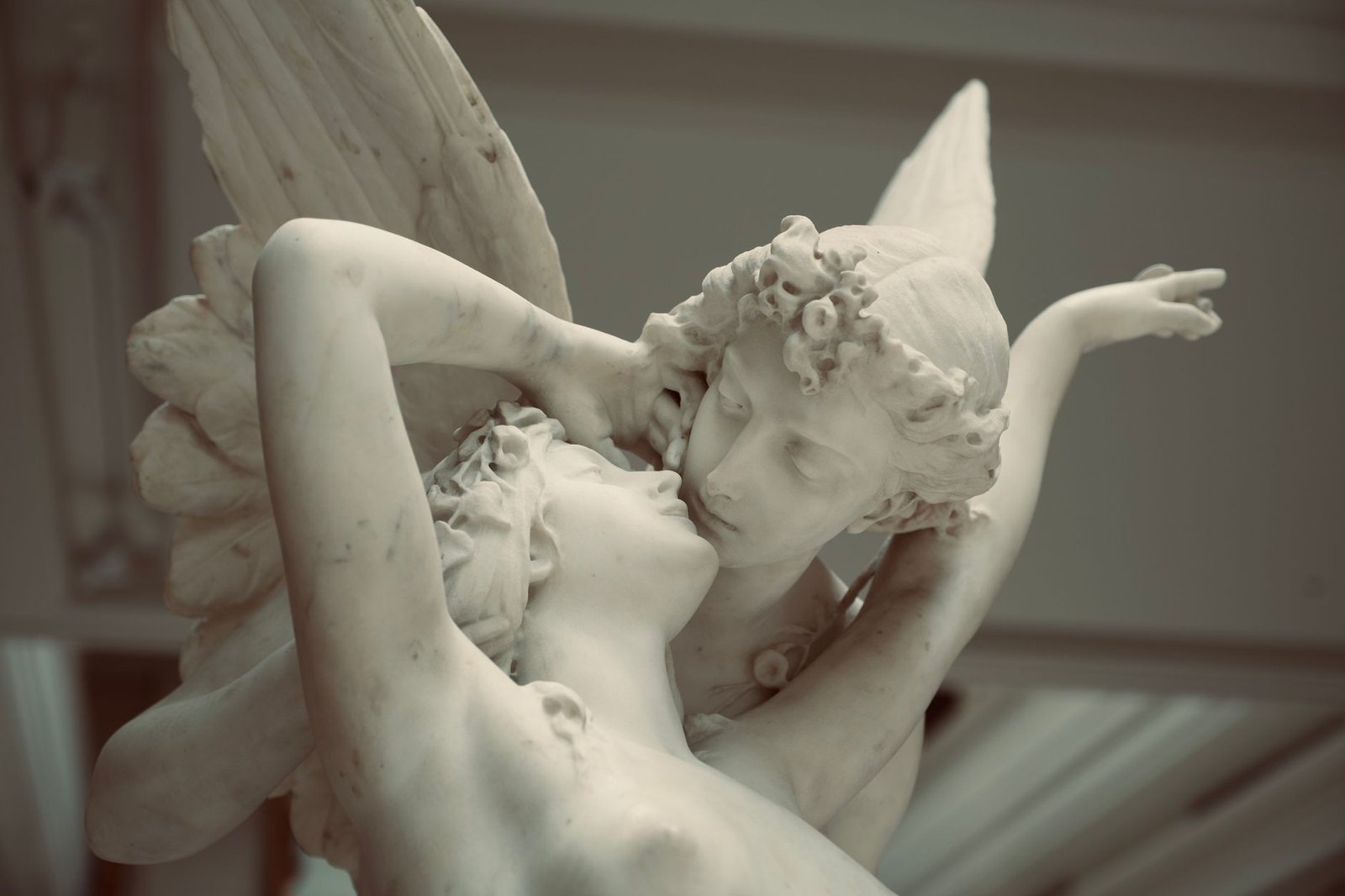 Close-up of a classical marble sculpture showing Cupid embracing another figure in an intimate pose.