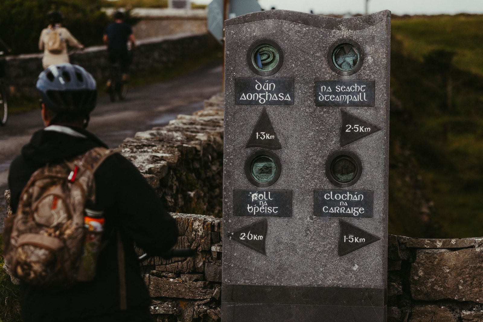 Stone signpost in the Irish countryside with directional markers and distances pointing different ways