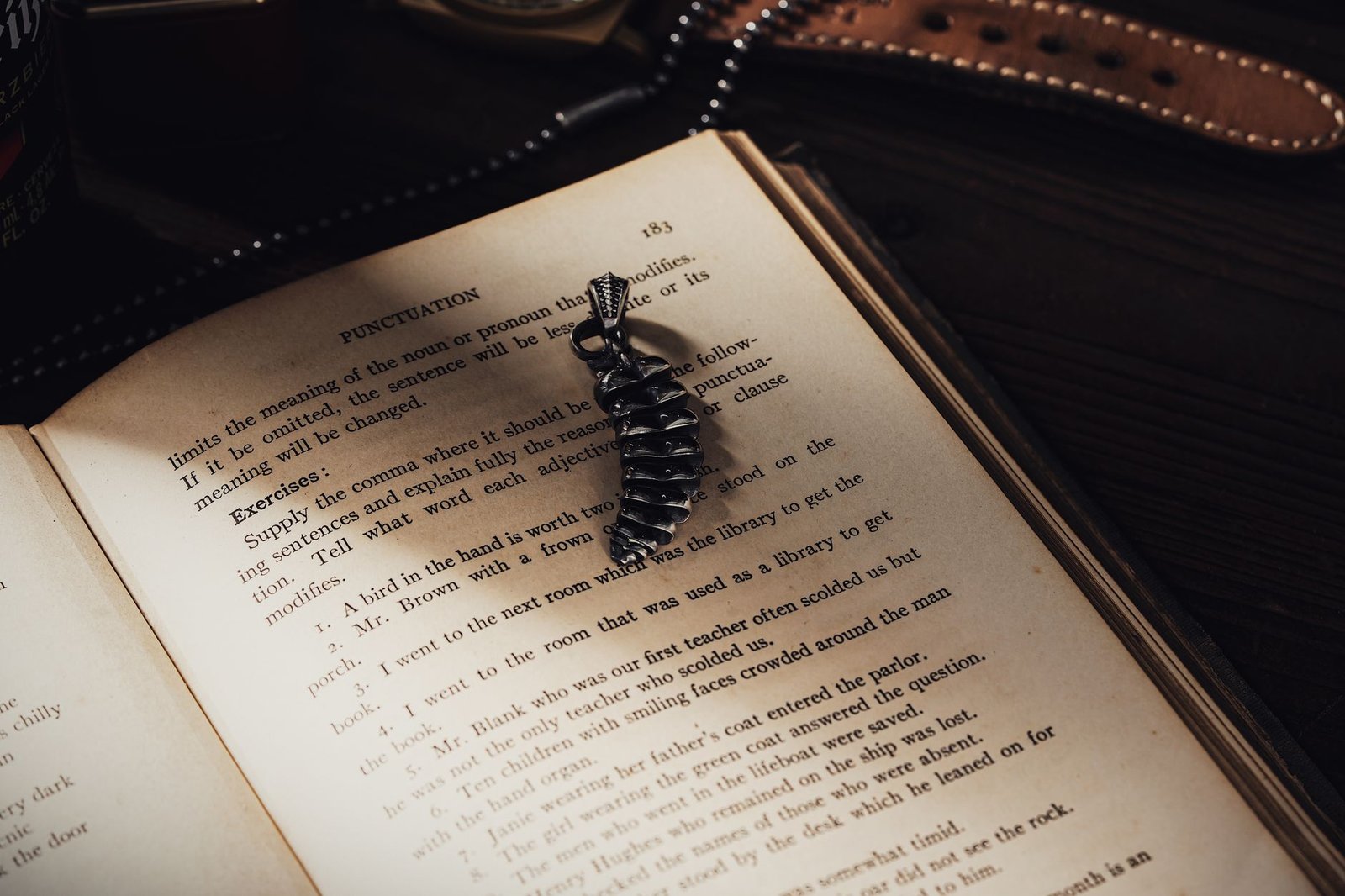 Open book with a feather-shaped magatama pendant resting on its pages