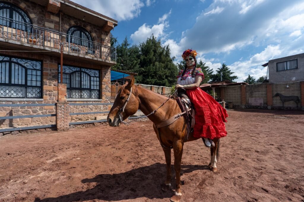 Woman in a red dress riding a horse in a rustic outdoor setting, evoking the Dullahan headless horseman legend