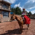 Woman in traditional dress riding a horse in a rustic outdoor setting, evoking Dullahan folklore