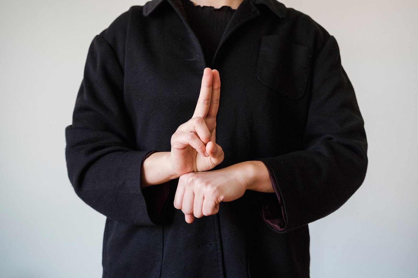 Person demonstrating a sign language gesture against a plain background