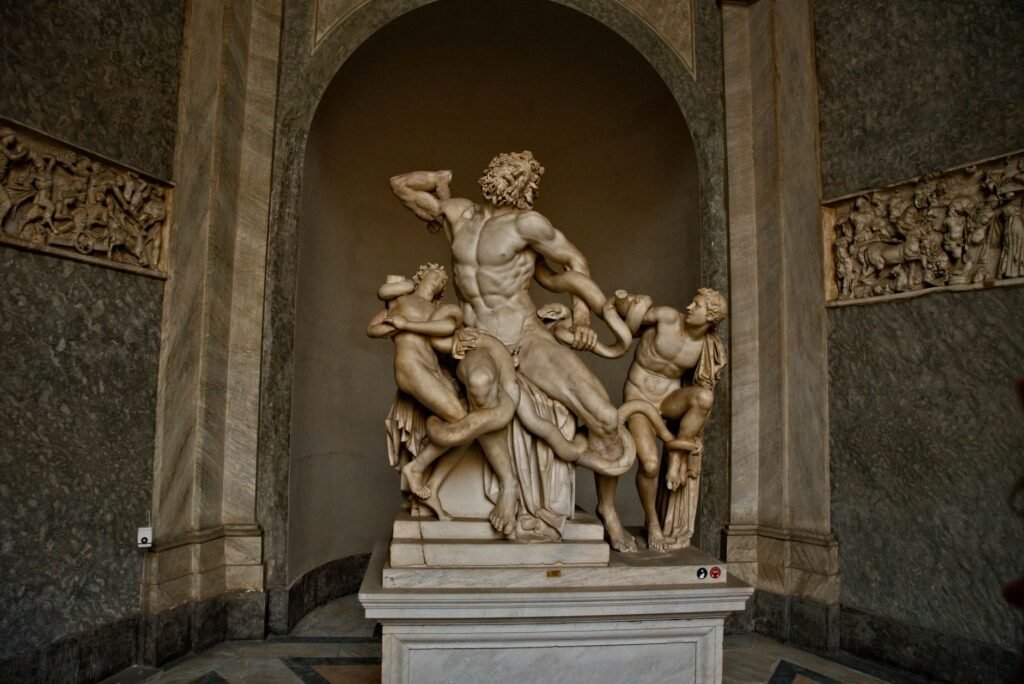 Marble statue of Laocoön and his sons in a museum niche, showing the mythological struggle with serpents