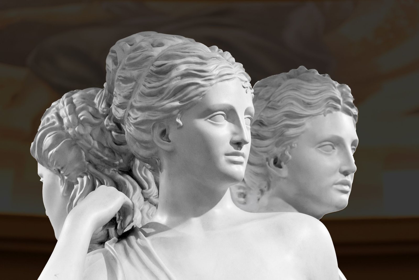 Close-up of a white marble sculpture of three female heads, likely the Roman goddess Flora depicted in classical style