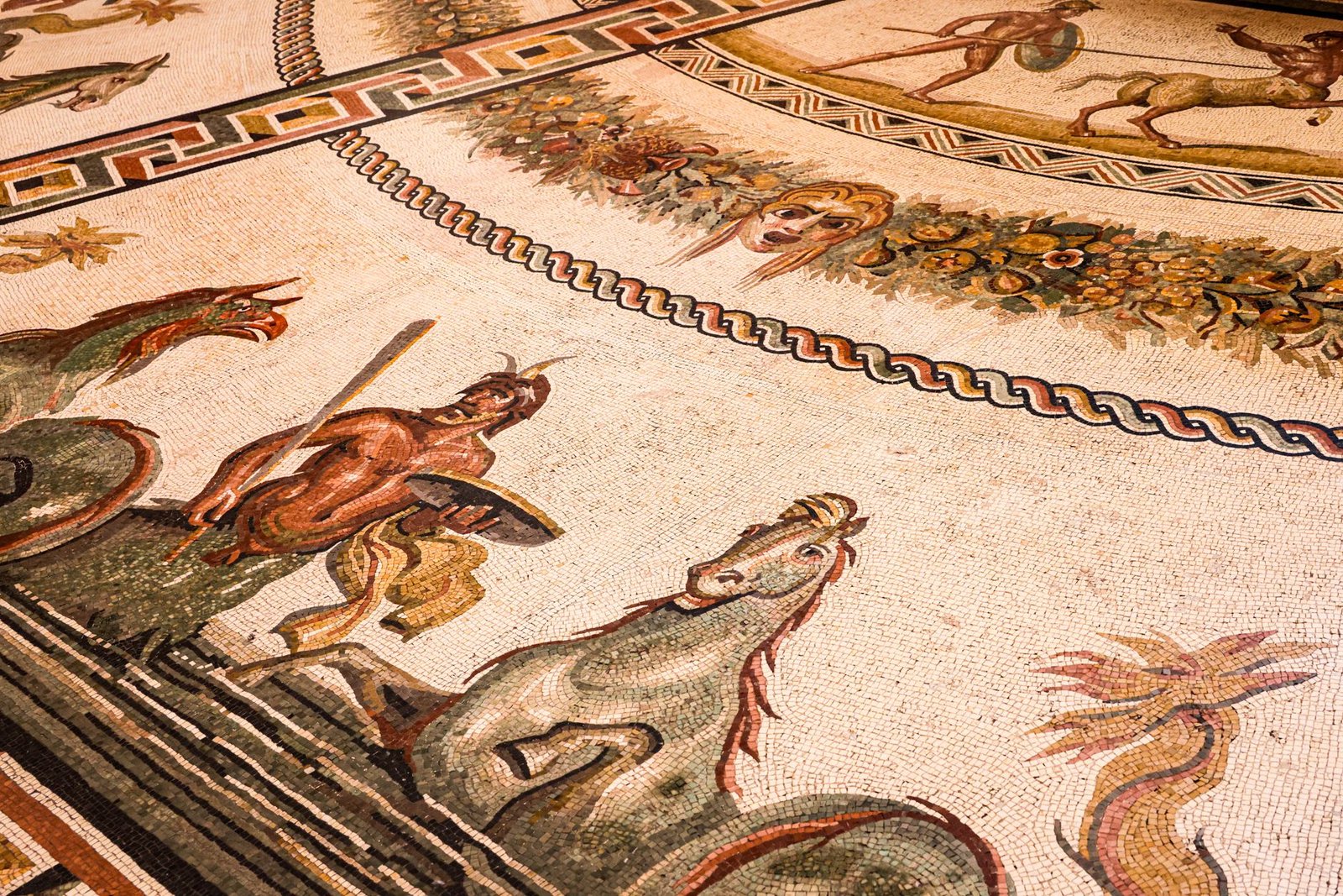 Ancient Roman mosaic showing mythological figures beside horses in a detailed floor scene