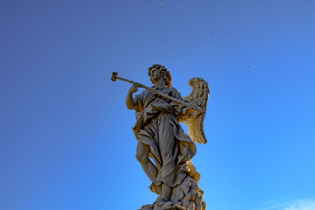 Angel statue playing a trumpet against a clear blue sky
