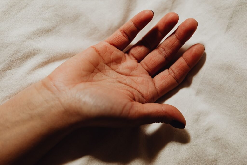 Open human hand resting on a white fabric surface
