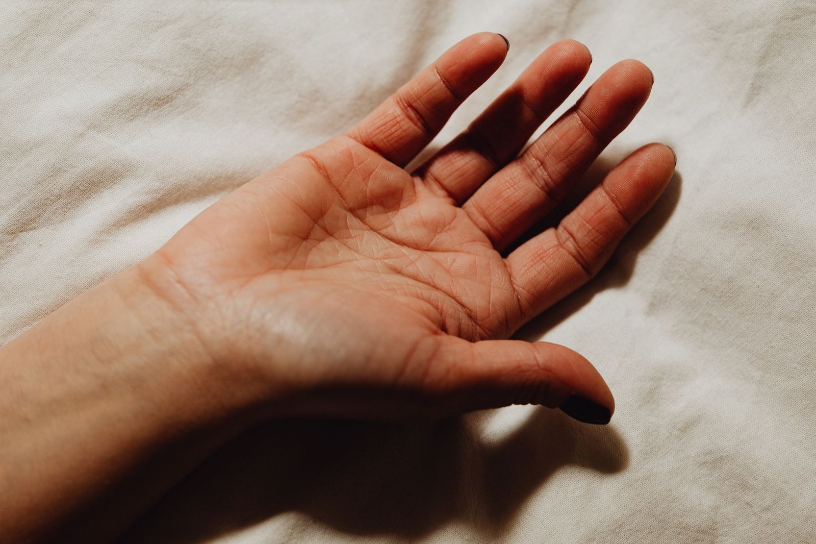 Open human hand resting on a white fabric surface