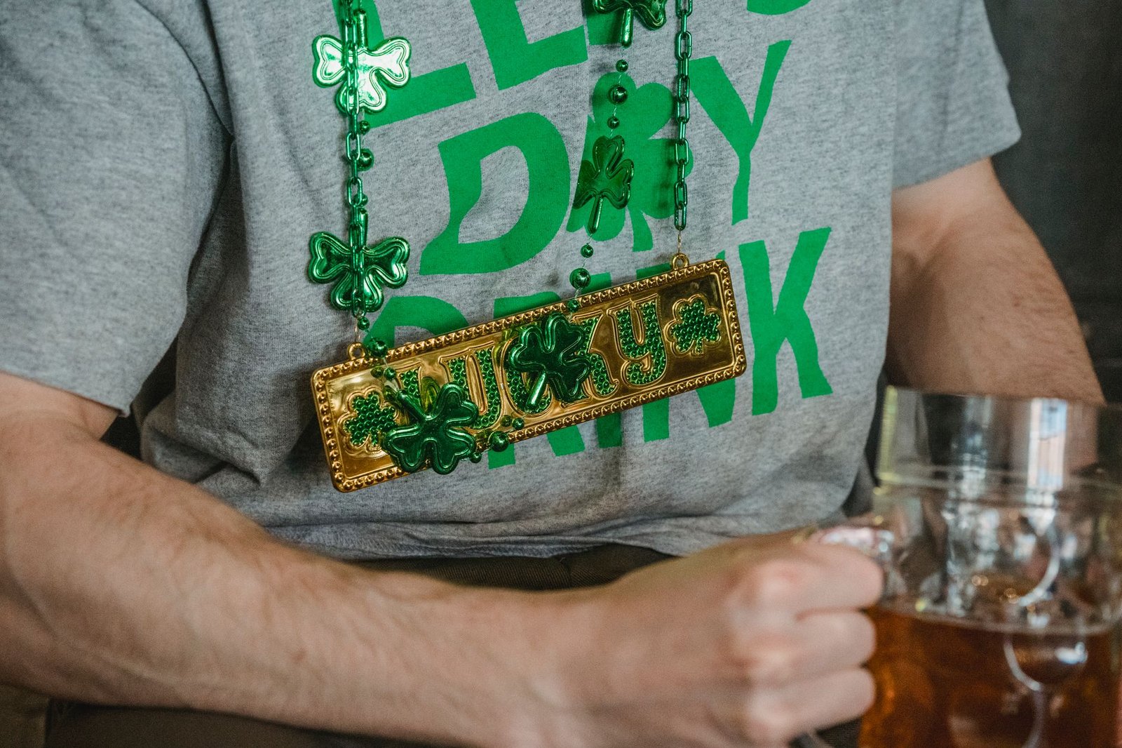 Man wearing a St. Patrick's Day necklace and holding a beer mug