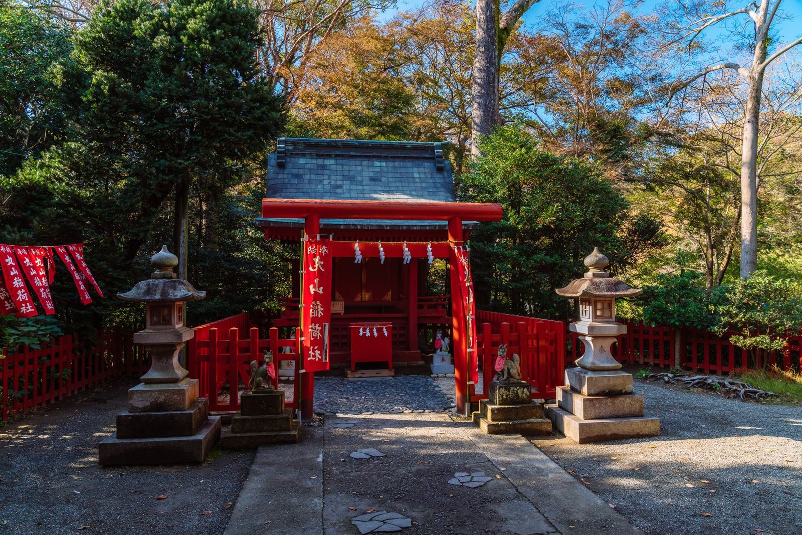 Red torii gate at a Hachiman shrine surrounded by autumn trees