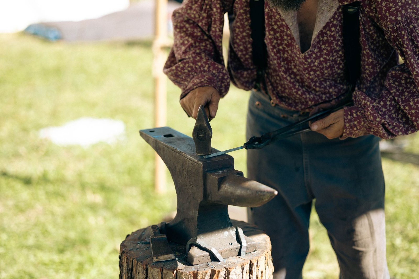 Vulcan shaping hot metal on an anvil outdoors with a hammer in a blacksmith scene