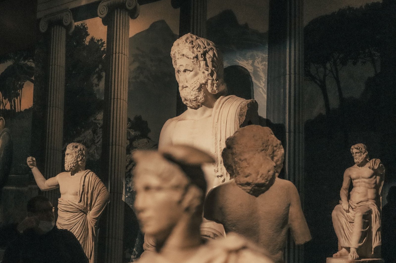 Ancient Greek marble statues displayed in a museum with classical columns in the background
