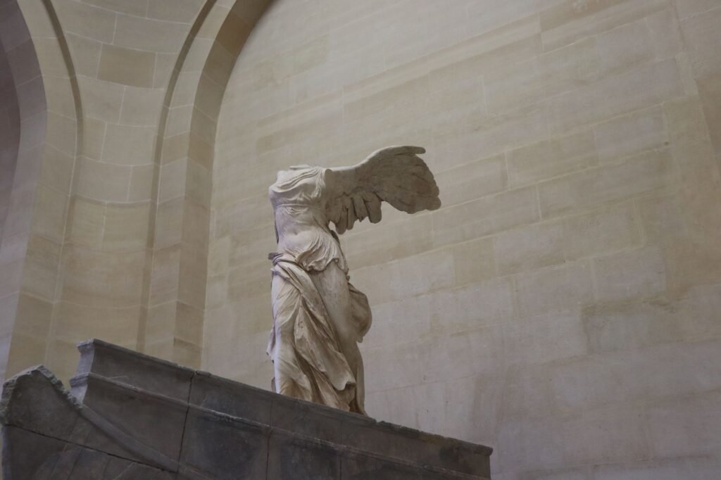 Ancient Greek marble Winged Victory of Samothrace statue displayed on a museum pedestal