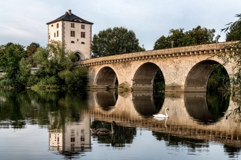 Historic stone bridge with arches and a tower reflected in calm river water, evoking Horatius at the Bridge