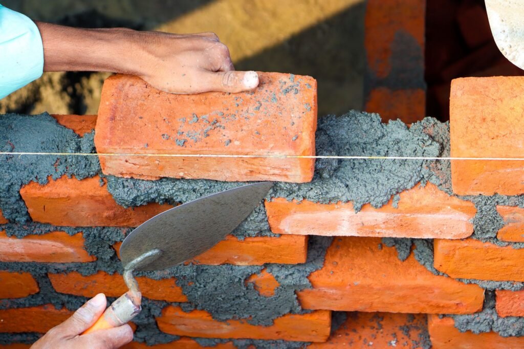 Bricklayer using a trowel and mortar to build a brick wall, representing the builder of Asgards wall