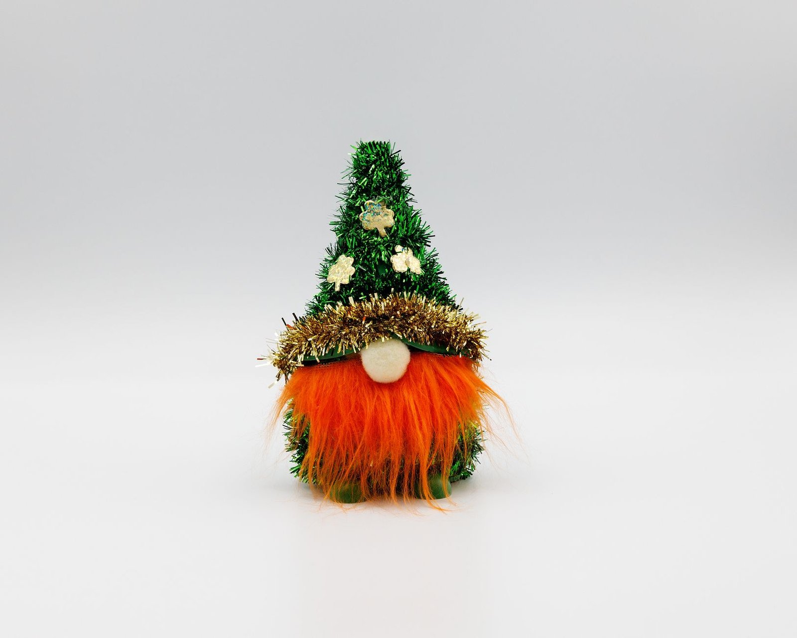 Small Christmas gnome decoration with green hat and orange beard on a white background