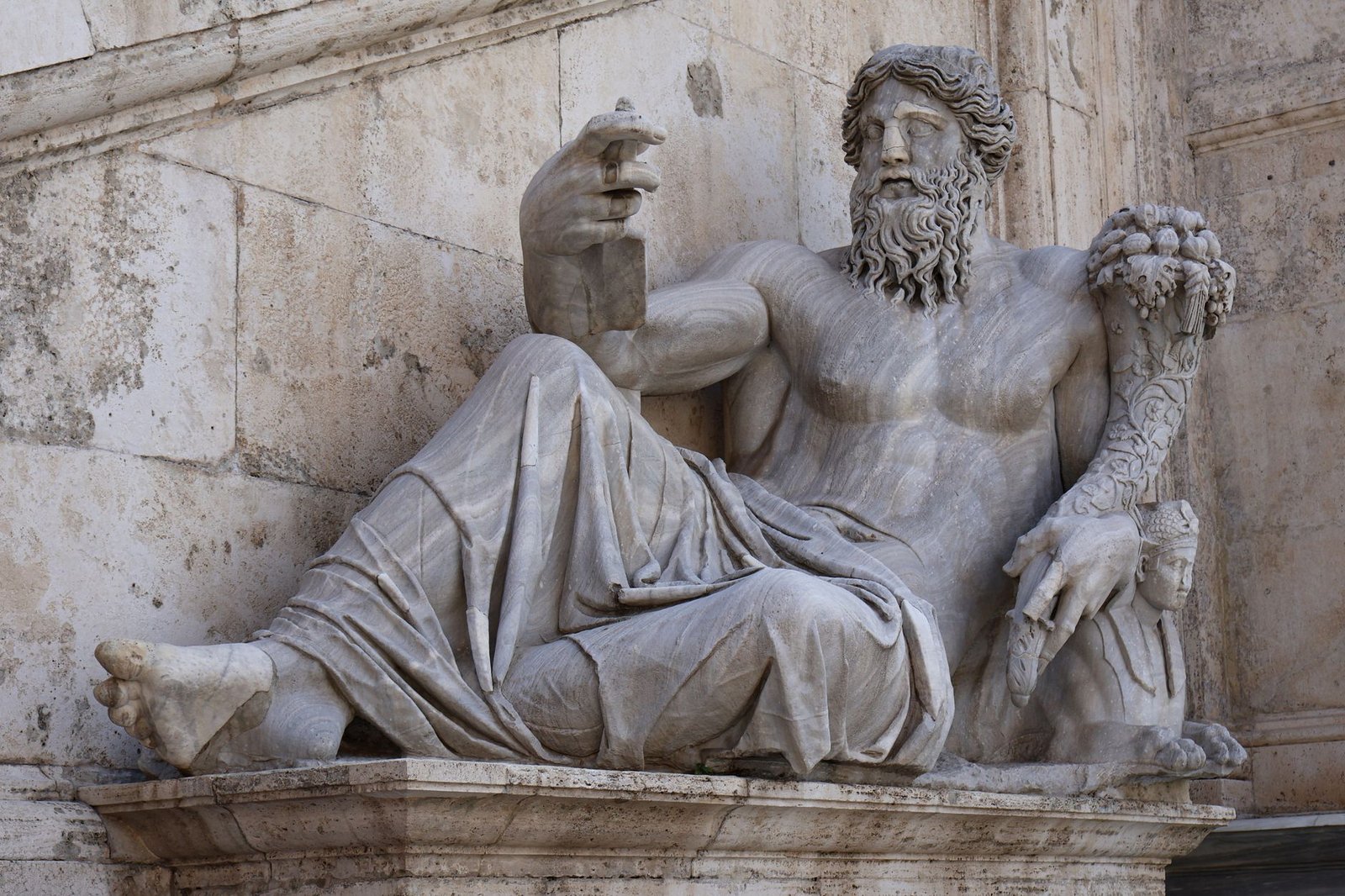 Ancient marble statue of a reclining bearded man with a lion beside him, representing Jupiter, the Roman god