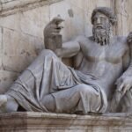 Ancient marble statue of a reclining bearded man with a lion beside him, evoking Jupiter, Roman god of the sky
