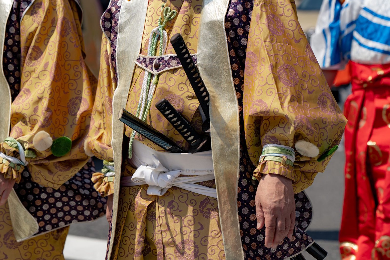 Japanese samurai in traditional attire wearing swords at a cultural festival, including Kusanagi no Tsurugi symbolism