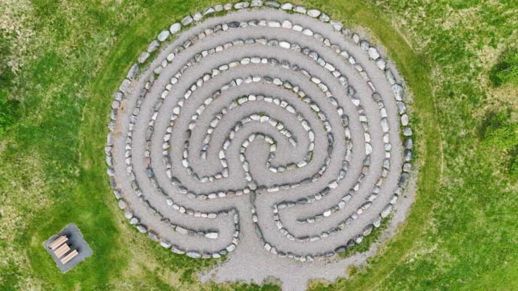 Aerial view of a circular stone labyrinth set in green grass
