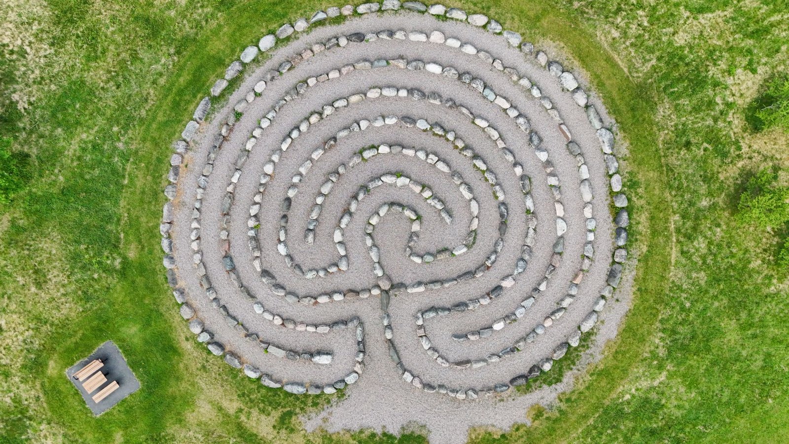 Aerial view of a circular stone labyrinth set in green grass