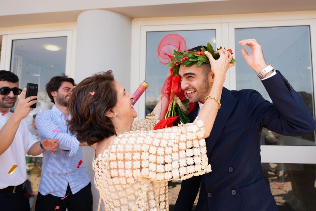 Happy graduate with friends as a woman places a laurel wreath on his head during a celebration