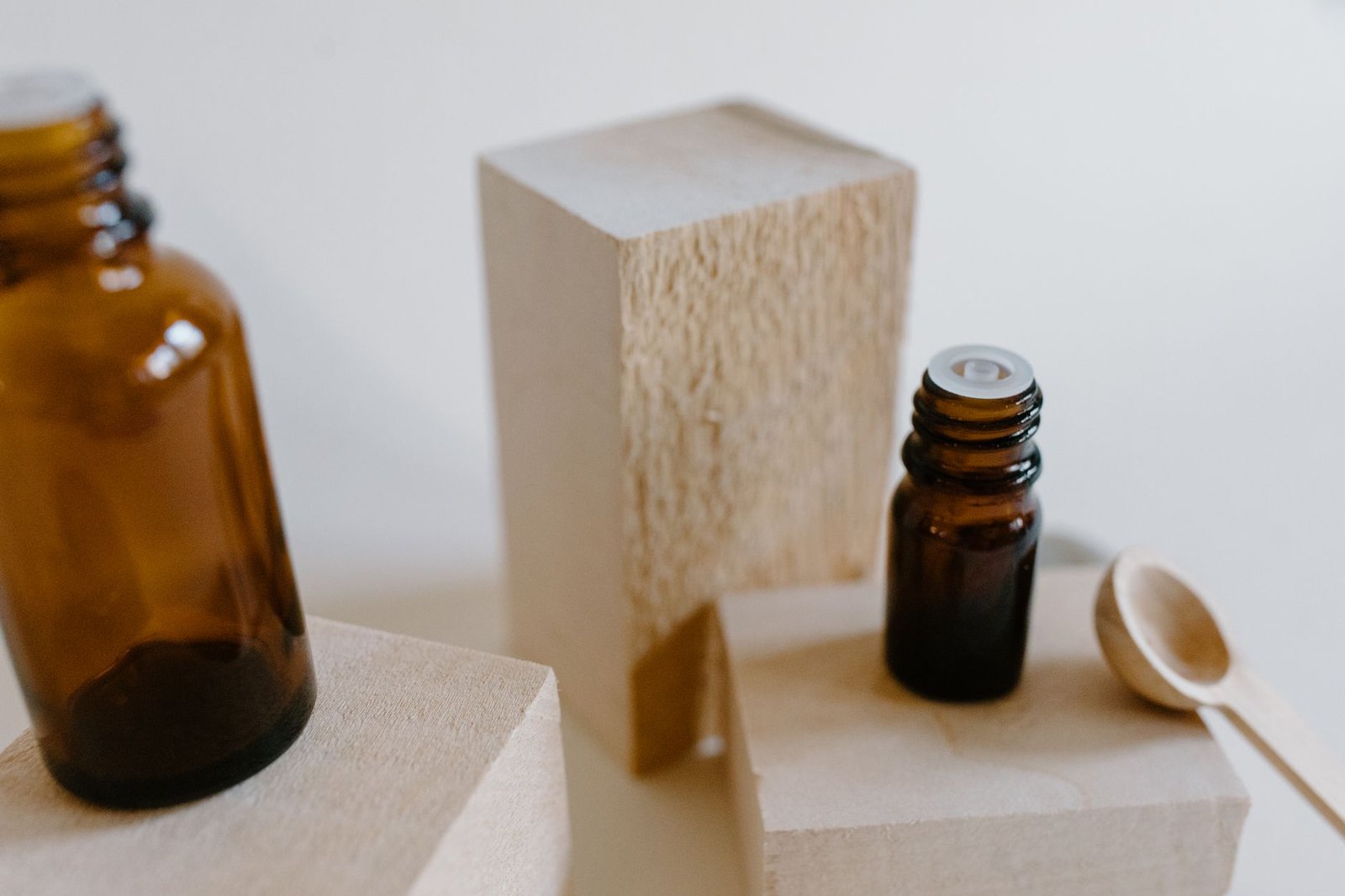 Amber glass bottles and wooden spoon on beige blocks, styled as natural skincare and evoking nectar and ambrosia