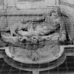 Reclining stone statue of Neptune, Roman sea god, in an architectural setting in black and white