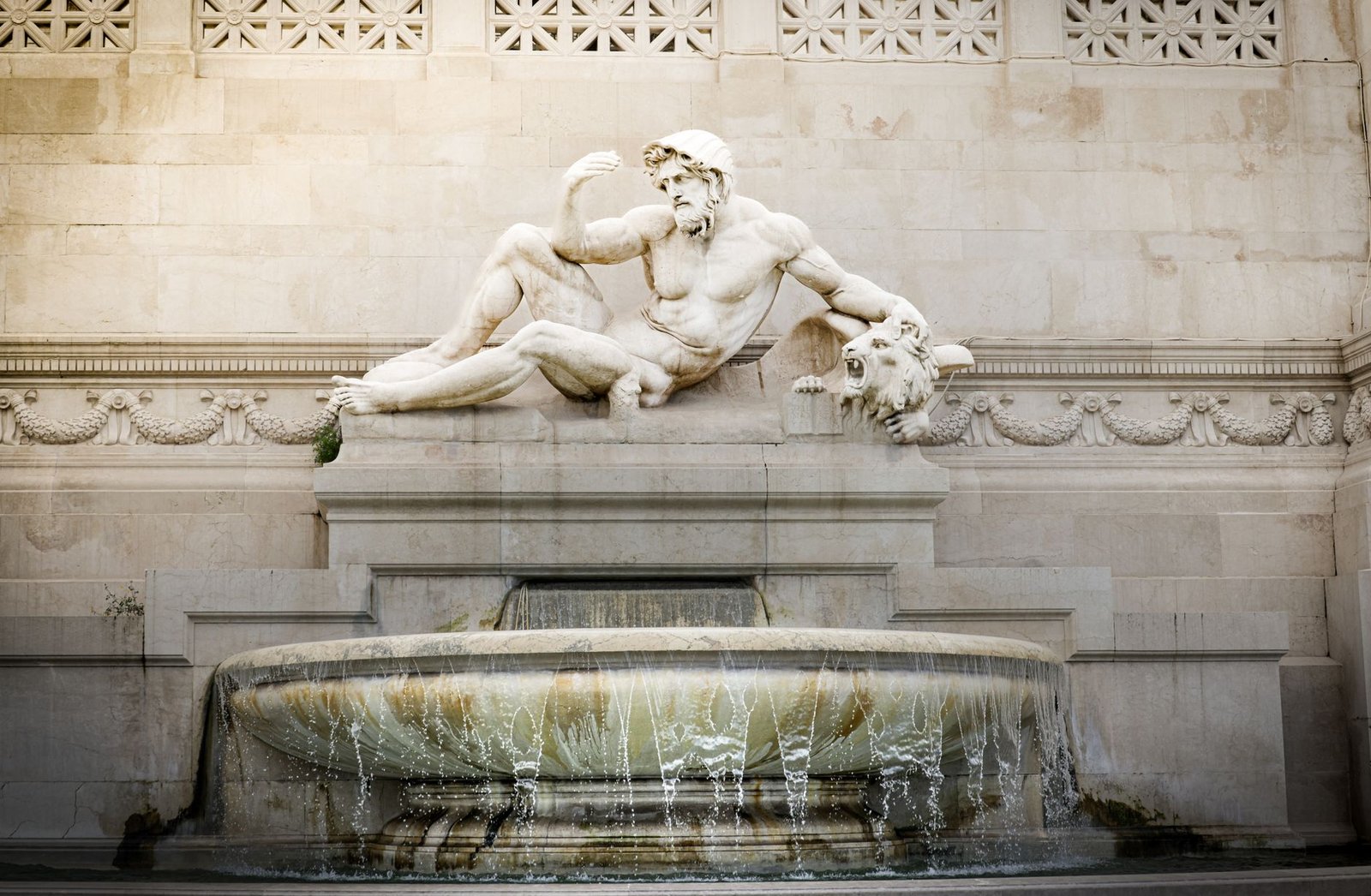Classical marble statue of a reclining male figure above an ornate stone fountain representing the Niobe myth