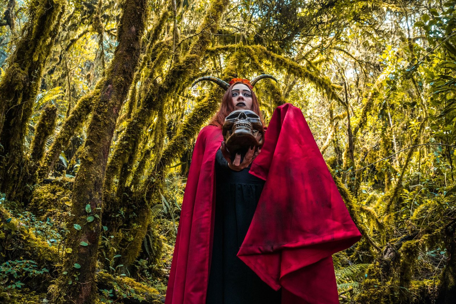 Woman in a red cloak holding a skull in a mystical forest, evoking Ogma in Irish mythology
