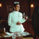 Woman in a white suit presenting in a dimly lit office setting